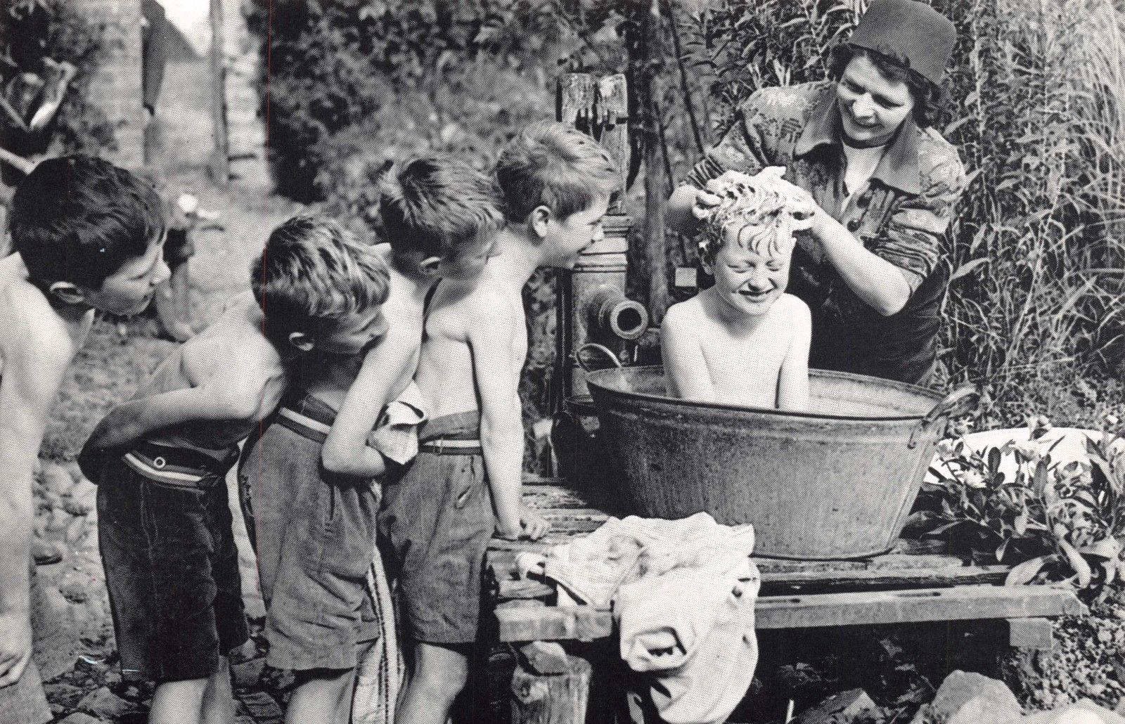 woman bathing children in cold water in an old vintage wash tub